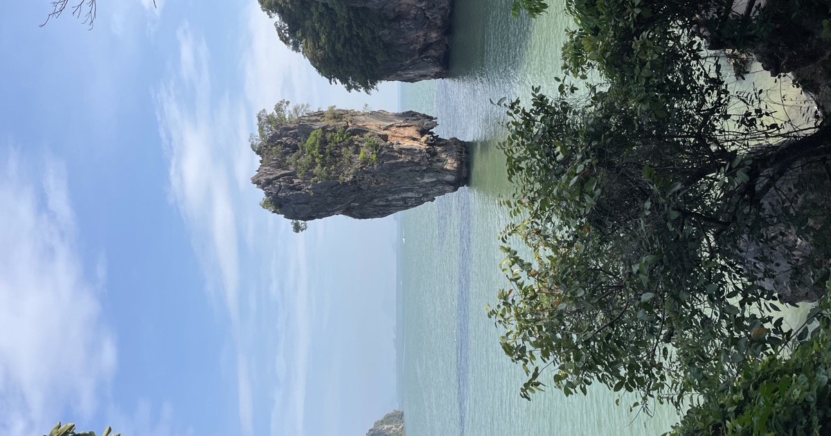 Un îlot karstique dressé dans une baie d'eau émeraude, sous un ciel dégagé